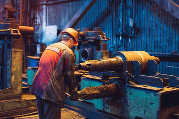 Heavy Industry Worker Working Hard on Machine. Rough Industrial Environment.
