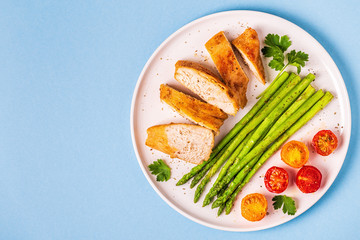 Roasted chicken breast with asparagus and tomatoes.
