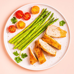 Roasted chicken breast with asparagus and tomatoes.