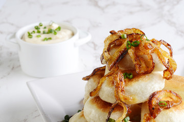 closeup pierogies with sour cream caramelized onions