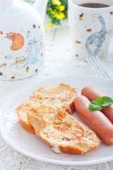 Breakfast with sausages and white bread, fried in eggs and milk, selective focus