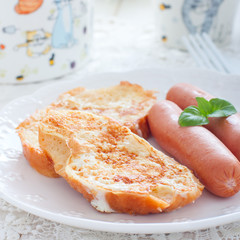 Breakfast with sausages and white bread, fried in eggs and milk, selective focus