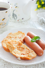 Breakfast with sausages and white bread, fried in eggs and milk, selective focus