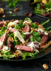 Grilled Beef Steak salad with pears, walnuts and greens vegetables and blue cheese sauce. healthy food.