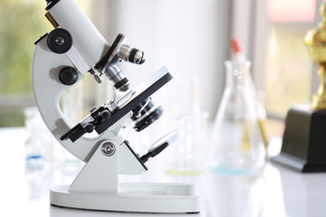 close up microscope in science room with test tube background