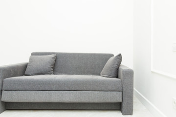 Classic modern gray sofa with pillows in the bright interior of the apartment