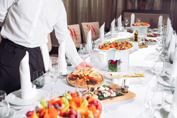 Waiter serving table in the restaurant preparing to receive guests.