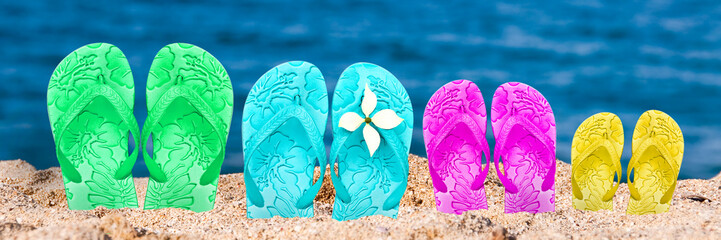 Flip flops of family on a beach, panoramic summer background with copy space