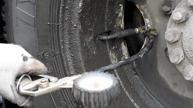 The pump inflates the dirty wheel in the rain in natural light Inflatable tyre compressor with black hose and external pressure sensor in rainy weather
