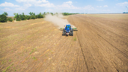 Naklejka premium A tractor plowing and sowing in the field