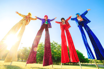 Young people on stilts posing against the blue sky.