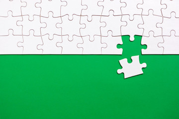 Green background made from white jigsaw puzzle pieces and place for your content
