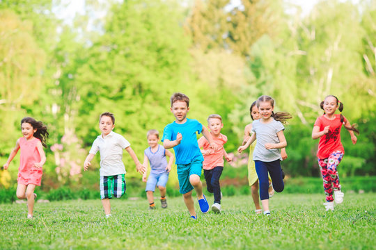 Many different kids, boys and girls running in the park on sunny summer day in casual clothes