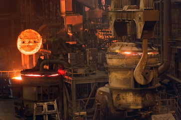 Melting of metal in a steel plant. High temperature in the melting furnace. Metallurgical industry. Factory for the manufacture of metal pipes. Bucket for feeding metal into molds.