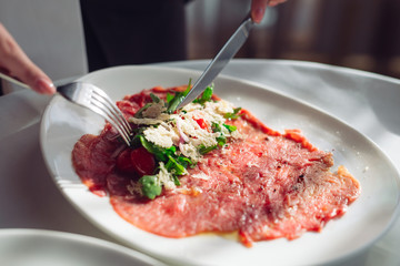 Red beef carpaccio in a white plate,
