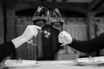 Man and woman drinking red wine. In the picture, close-up hands with glasses.
