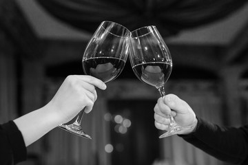 Man and woman drinking red wine. In the picture, close-up hands with glasses.
