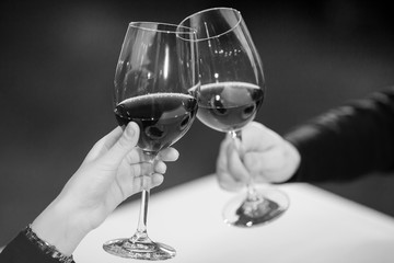 Man and woman drinking red wine. In the picture, close-up hands with glasses.