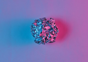 Crumpled paper ball enveloping neon blue pink light. Top view, surrealism