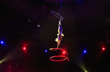 Aerial acrobat in the ring. A young girl performs the acrobatic elements with tape in the air ring.