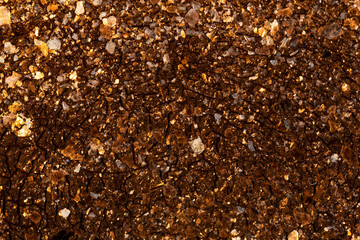 Textured surface from which the bright, magical, golden rays of the setting sun are reflected. Background.