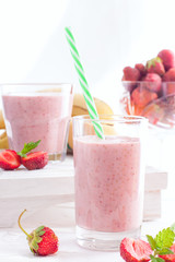 Smoothies of strawberries and bananas in glass glasses on a white table, selective focus