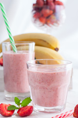 Smoothies of strawberries and bananas in glass glasses on a white table, selective focus