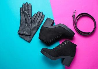 Minimalism collage of fashionable women's shoes and accessories on pink blue background. Black boots, leather gloves, belt. Top view