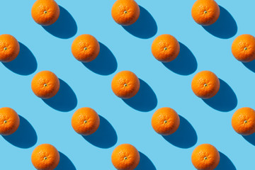 One orange on a blue background. Hard light. Tropics concept, healthy food, breakfast, diet, vacation. Flat lay, top view. pattern