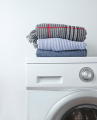Stack of clothes on washing machine against a white background