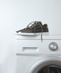Sport sneakers on washing machine against a white background
