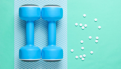 Sport concept. Dumbbells, pills on blue background. Minimalism. Top view