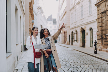 Two joyful young women with map exploring the old city