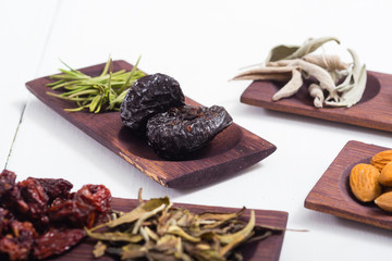 dried fruits and spices on wooden tray, white table