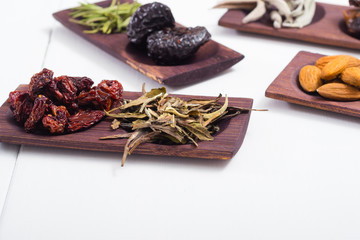 dried fruits and spices on wooden tray, white table