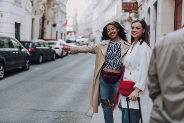 Fototapeta premium Two charming young women trying to stop taxi car