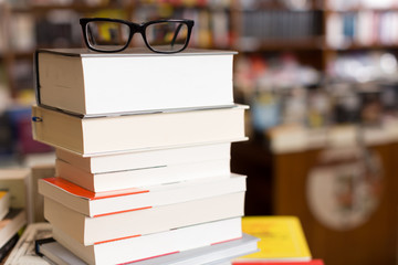 glasses on top of different books lying on table in school library