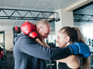Fototapeta na wymiar Loving couple embraces in boxing gloves and looks at each other's eyes in the gym.