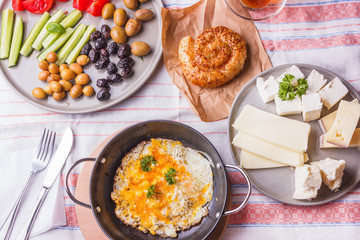Traditional Turkish breakfast - fried eggs, fresh vegetables, olives, cheese, cake and tea