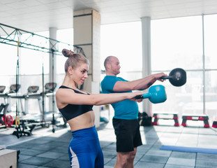 Fototapeta na wymiar Сouple functional training. Sporty man and fit woman doing exercise with kettlebell in gym