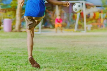 Asian boys practice kicking the ball to score goals in the public football field.