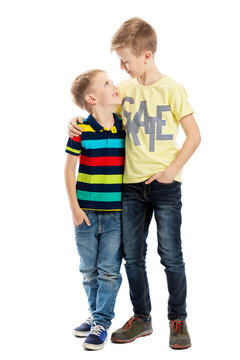 Two brothers embrace and smile, looking at each other. Friendship and love. Isolated on a white background. Vertical.