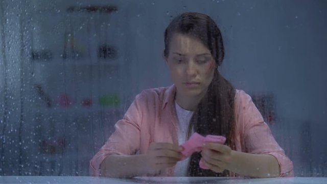 Sad wounded face lady holding pink socks on rainy day, misbirth after violence