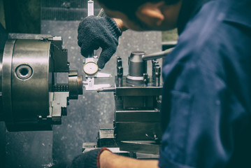 The lathe machine operator measure the inside diameter of metal part with vernier calliper. The retro scene of workshop operation. - Powered by Adobe