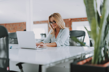 Confident woman working on the laptop and looking glad