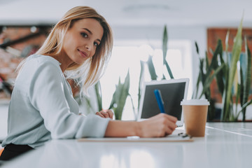 Woman in blue blouse writing at the table in her office