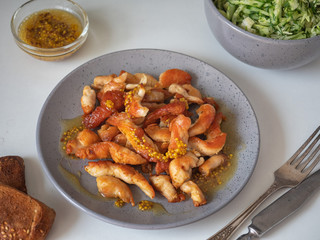 Fried chicken breast sliced in small pieces on a gray plate, shot at close range and cutlery on a white background.