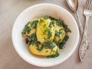 Boiled potatoes with herbs in a deep plate shot at close range