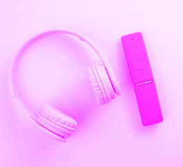 Wireless headphones, modern TV remote. Duotone effect. Home relaxation concept. Top view