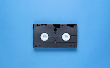 Obraz premium Pop culture retro attributes 80s, video cassette on blue background. Top view